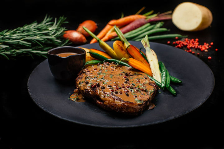 Grilled ribeye steak with creamy peppercorn sauce on a plate
