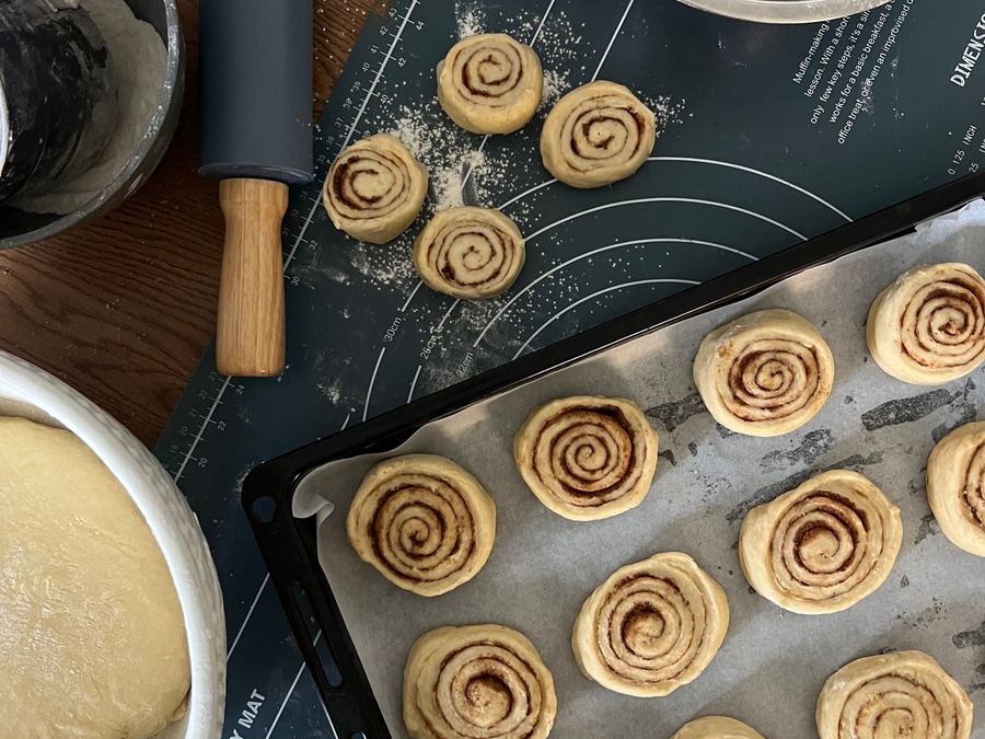 Cinnamon rolls being prepared with dough and spice