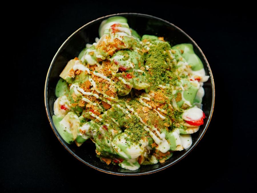 A bowl topped with green powder and fresh fruit