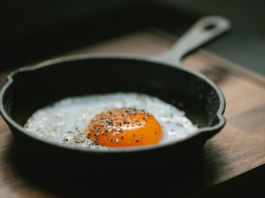 A fried egg in a pan finished with black pepper