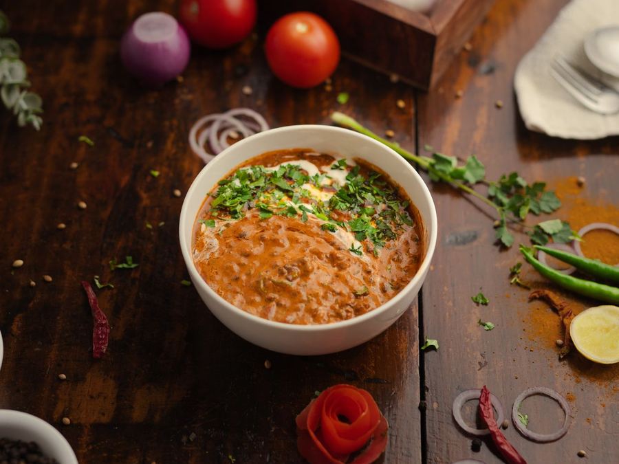 A bowl of dal with fresh ingredients alongside